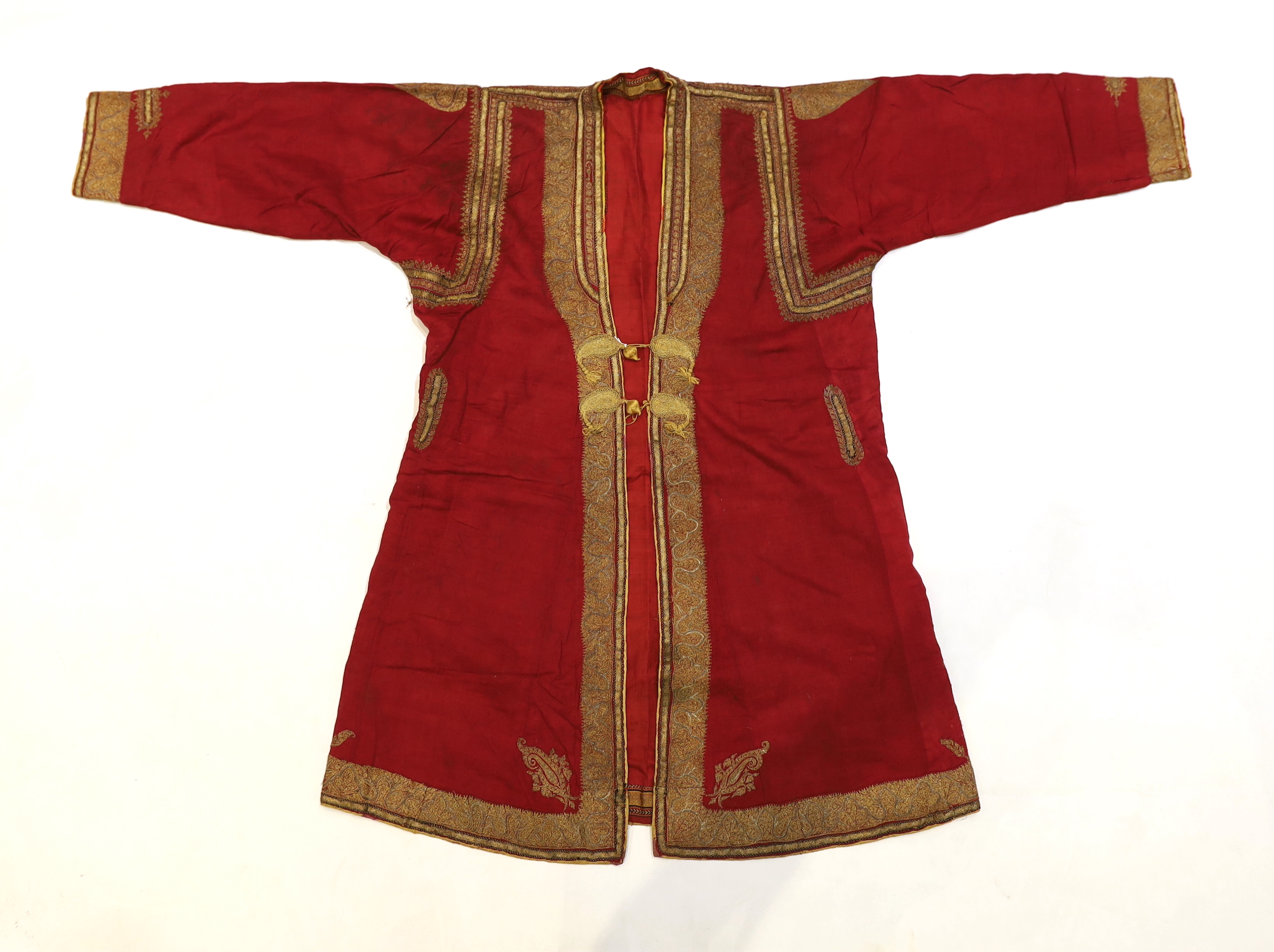 A late 19th century gentleman’s quilted red silk Indian Chogha, embroidered with ornate gold and silver metallic thread borders and paisley design details